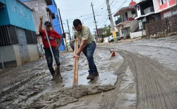 A man removes the mud left by the flooding after the rains related to the passage of Hurricane Maria, in Toa Baja, Puerto Rico, on September 22, 2017.Puerto Rico battled dangerous floods Friday after Hurricane Maria ravaged the island, as rescuers raced against time to reach residents trapped in their homes and the death toll climbed to 33. Puerto Rico Governor Ricardo Rossello called Maria the most devastating storm in a century after it destroyed the US territory's electricity and telecommunications infrastructure. / AFP PHOTO / HECTOR RETAMAL