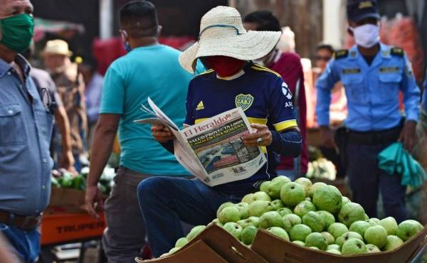 A man wears a face mask against the spread of the new coronavirus as he reads a newspaper at a market in Tegucigalpa on April 8, 2020. - 312 cases of COVID-19 were reported in Honduras, with 22 deaths. (Photo by ORLANDO SIERRA / AFP)