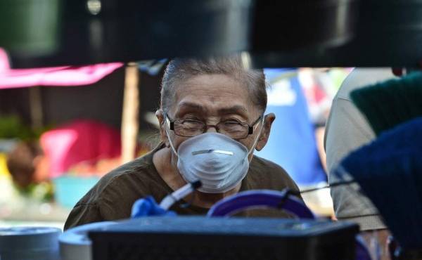 A woman wears a protective face mask to prevent the spread of the new Coronavirus, at the Agriculture Market, in Tegucigalpa, on March 14, 2020. - Honduran government has prohibited citizens from Europe, China, Iran, and South Korea the entrance to the country. (Photo by ORLANDO SIERRA / AFP)