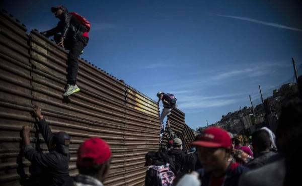 A group of Central American migrants -mostly Hondurans- climb the border fence between Mexico and the United States, near El Chaparral border crossing, in Tijuana, Baja California State, Mexico, on November 25, 2018. - Hundreds of migrants attempted to storm a border fence separating Mexico from the US on Sunday amid mounting fears they will be kept in Mexico while their applications for a asylum are processed. An AFP photographer said the migrants broke away from a peaceful march at a border bridge and tried to climb over a metal border barrier in the attempt to enter the United States. (Photo by Pedro PARDO / AFP)