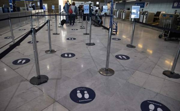 Stickers mark out social distancing spacing on the floor at the check-in queue for Air France in Terminal 2 of Charles de Gaulle international airport in Roissy near Paris, on May 14, 2020, as France eases lockdown measures taken to curb the spread of the COVID-19 (the novel coronavirus). (Photo by Ian LANGSDON / EPA POOL / AFP)