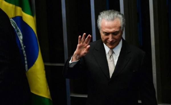 President Michel Temer waves as he takes office before the plenary of the Brazilian Senate in Brasilia, on August 31, 2016. Brazil's Dilma Rousseff was stripped of the country's presidency in an impeachment vote Wednesday and replaced by her bitter rival Michel Temer, shifting Latin America's biggest economy sharply to the right. / AFP PHOTO / ANDRESSA ANHOLETE