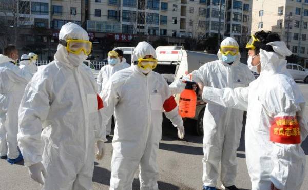 This photo taken on February 18, 2020 shows members of a police sanitation team having their protective suits disinfected after they sprayed disinfectant in the streets as a preventive measure against the spread of the COVID-19 coronavirus in Bozhou, in China's eastern Anhui province. - The death toll from China's new coronavirus epidemic jumped past 2,000 on February 19 after 136 more people died, with the number of new cases falling for a second straight day, according to the National Health Commission. (Photo by STR / AFP) / China OUT