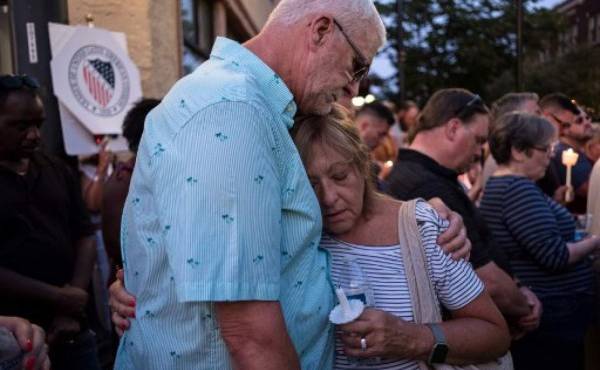 Personas se abrazan tras encender una fela en la vigilia para recordas a las víctimas del tiroteo en Dayton, Ohio el 4 de agosto de 2019. (Photo by Megan JELINGER / AFP)
