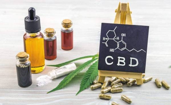 Full spectrum Cannabidiol CBD oils, capsules and crystals isolate with small blackboard with CBD word and chemical structure on wooden backdrop