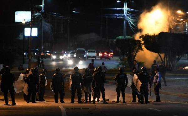 Members of the militar police release tear gas to the protestants in Tegucigalpa on June 19, 2019, during a day of protests against government reforms. - Thounsands of teachers, doctors and students have been staging protest against the government of Honduran President Juan Orlando Hernandez for measures they say will privatize health and education services. (Photo by ORLANDO SIERRA / AFP)