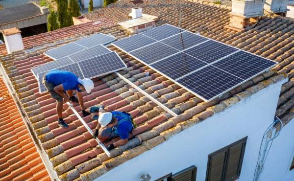 aerial view of two workers installing the guides to place a solar panel in the roof