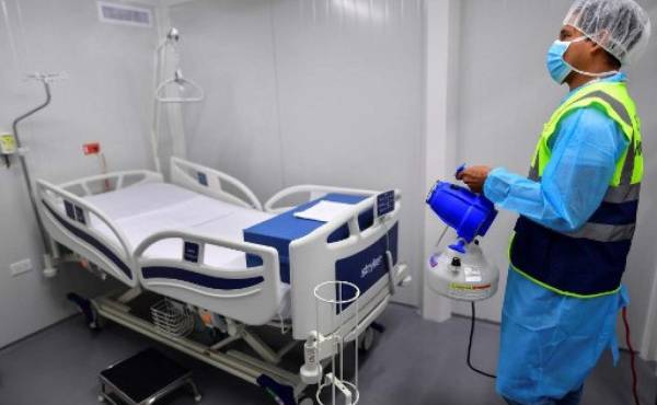 Un empleado pone desinfectante en un cuarto intergrado del Hospital 'Panama Solidario' para pacientes crónicos por COVID-19 en Ciudad de Panamá. (Foto de Luis ACOSTA / AFP)