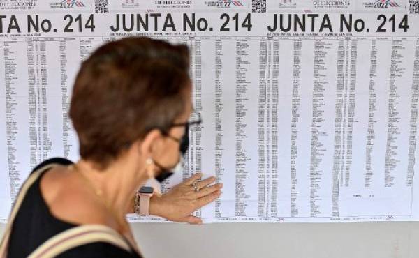 A woman looks at a chart to find the polling station where to vote during general elections in San Jose, on February 6, 2022. - Costa Ricans head to the polls Sunday with a crowded presidential field and no clear favorite for tackling growing economic concerns in one of Latin America's stablest democracies. (Photo by Luis ACOSTA / AFP)