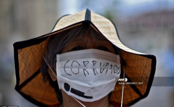 A woman wears a face mask reading Corrupt during a protest in demand of the resignation of Guatemalan President Alejandro Giammattei, at Constitution Square in Guatemala City on August 22, 2020, amid the COVID-19 coronavirus pandemic. (Photo by Johan ORDONEZ / AFP)