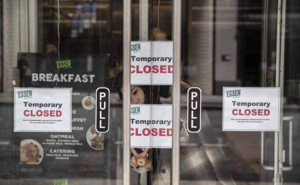 NEW YORK, NY - MARCH, 17: A woman hangs a sign in a restaurant due to closures in the wake of the Coronavirus, COVID19, outbreak on March 17, 2020 in New York City. Schools, businesses and most places where people congregate across the country have been shut down as health officials try to slow the spread of COVID-19. Victor J. Blue/Getty Images/AFP