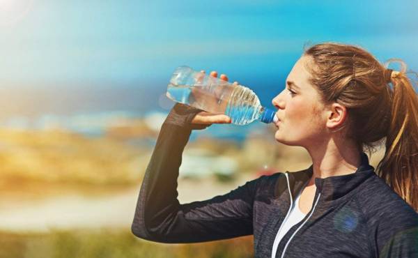 Shot of a sporty young woman drinking water outdoors