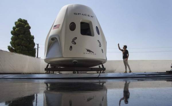 HAWTHORNE, CA - AUGUST 13: A reporter takes a smart phone photo of a mock up of the Crew Dragon spacecraft during a media tour of SpaceX headquarters and rocket factory on August 13, 2018 in Hawthorne, California. SpaceX plans to use the spaceship Crew Dragon, a passenger version of the robotic Dragon cargo ship, to carry NASA astronauts to the International Space Station for the first time since the Space Shuttle program was retired in 2011. David McNew/Getty Images/AFP