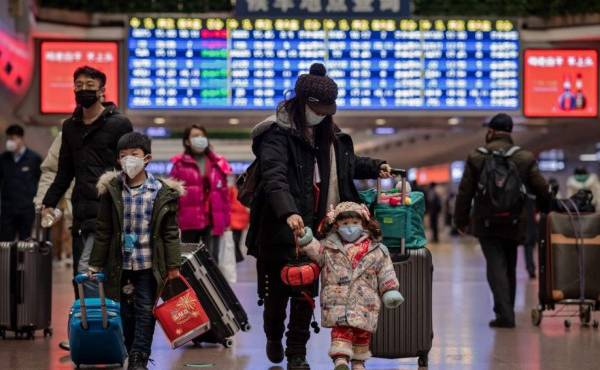A girl (C), wearing a face mask, holds the finger of her mom and a lantern as they travel back home for the Lunar New Year holidays, at Beijing West Railway Station in Beijing on January 24, 2020. - Chinese authorities rapidly expanded a mammoth quarantine effort aimed at containing a deadly contagion on January 24 to 13 cities and a staggering 41 million people, as nervous residents were checked for fevers and the death toll climbed to 26. (Photo by NICOLAS ASFOURI / AFP)