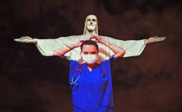 View of the world famous Christ the Redeemer statue on Easter day with a medical worker projected on it in honour of all the medical staff fighting the COVID-9 coronavirus pandemic worldwide in Rio de Janeiro, Brazil on April 12, 2020. (Photo by CARL DE SOUZA / AFP)