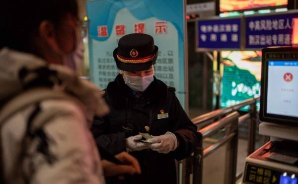 Un controlador ferroviario verifica la identificación de un viajero a su llegada a la estación principal de trenes de Wuhan el 10 de enero de 2021, la víspera del primer aniversario de China que confirma su primera muerte por el coronavirus Covid-19. (Foto de NICOLAS ASFOURI / AFP)