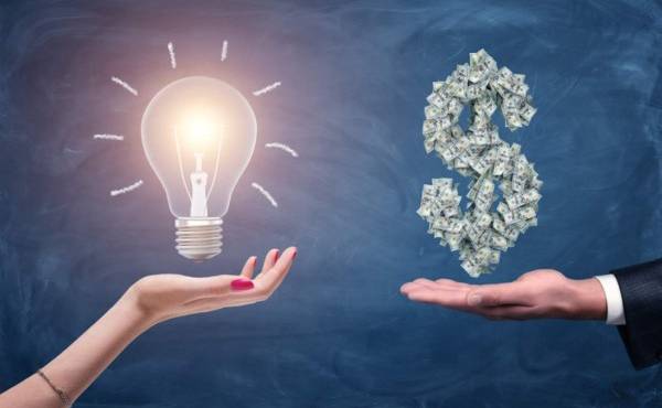 A female and a male hands holding a large bright light bulb and a dollar sign made of many money bills. Money and wealth. Profitable ideas. Financial streak.
