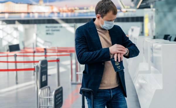 Un turista revisa su reloj en un aeropuerto antes de viajar.