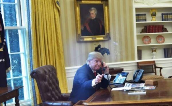 US President Donald Trump(L)seen through an Oval Office window, speaks on the phone to King Salman of Saudi Arabia in the Oval Office of the White House on January 29, 2017 in Washington, DC.Trump is speaking by phone with the leaders of Saudi Arabia and the United Arab Emirates, amid an uproar over his travel ban for some Muslim majority countries. / AFP PHOTO / Mandel Ngan