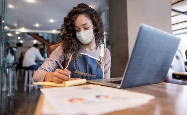 Business manager doing the books at a restaurant wearing a facemask to avoid coronavirus â pandemic lifestyle concepts