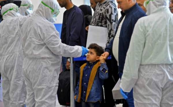 The body temperature of an Iraqi child returning from Iran is measured upon her arrival at the Najaf International Airport on February 21, 2020, after Iran announced cases of coronavirus infections in the Islamic republic. (Photo by Haidar HAMDANI / AFP)