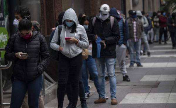 (FILES) In this file photo taken on May 28, 2020, people wear face masks as they queue to get an unemployment insurance outside the Chilean Unemployment Funds Administration headquarters in Santiago. - The coronavirus pandemic has left a trail of death around the world and has hit Latin America in particular, the new epicentre of a crisis that is shattering an already precarious labour market. (Photo by Martin BERNETTI / AFP)