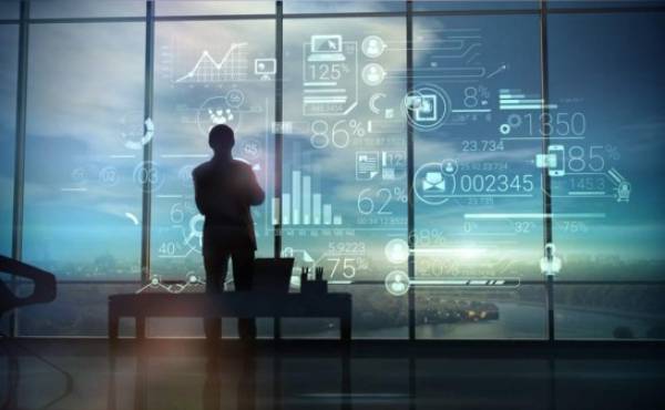 A silhouette of a man stands on the background of large office windows and views a hologram of corporate infographic with work data.