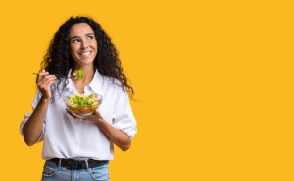 Cheerful Woman Eating Vegetable Salad From Bowl And Looking At Copy Space On Yellow Background, YoungLady Enjoying Heathy Nutrition And Organic Food, Having Vegetarian Meal For Lunch, Panorama
